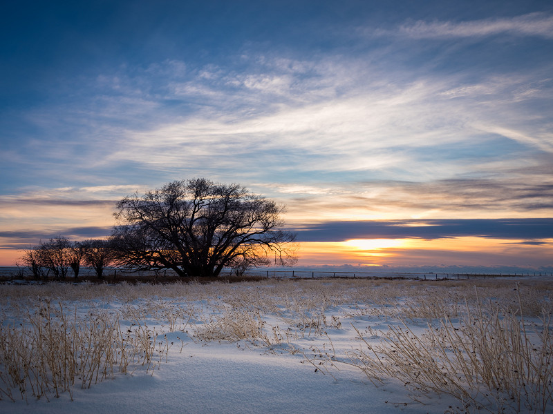 The sun sets over a snowy field